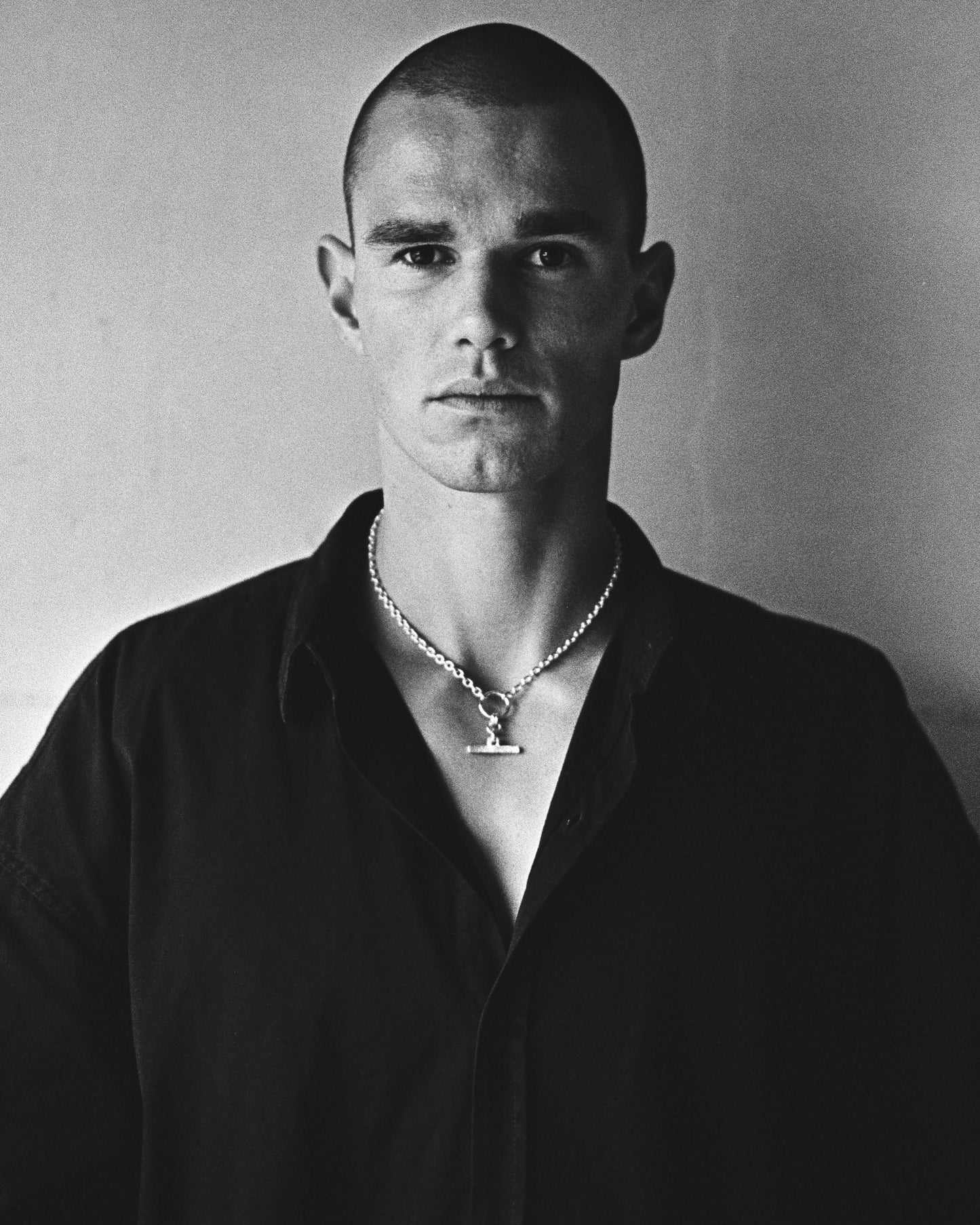 Styled male model shot showcasing a contemporary chain necklace featuring a textured fob pendant resting on the neck