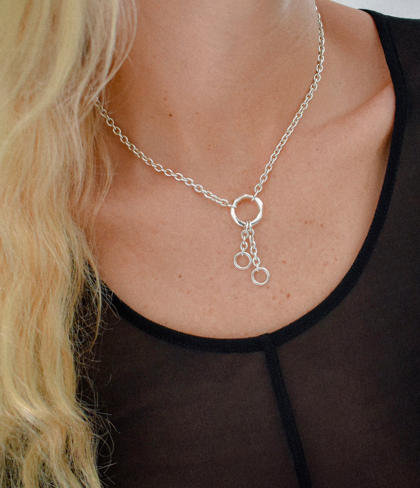 Sterling silver sculptural o-ring necklace styled on model. Features two hanging cable chains with mini o-rings, highlighting modern, minimal jewellery design