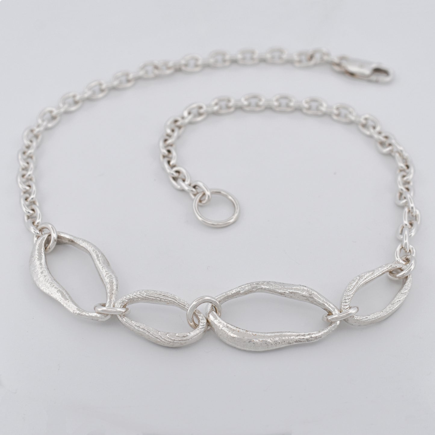 Sterling silver chain necklace featuring four sculptural links with raw textures
