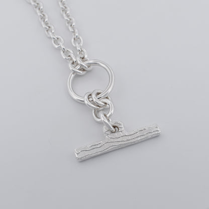 Detailed close-up of a contemporary chain necklace highlighting the textured fob pendant