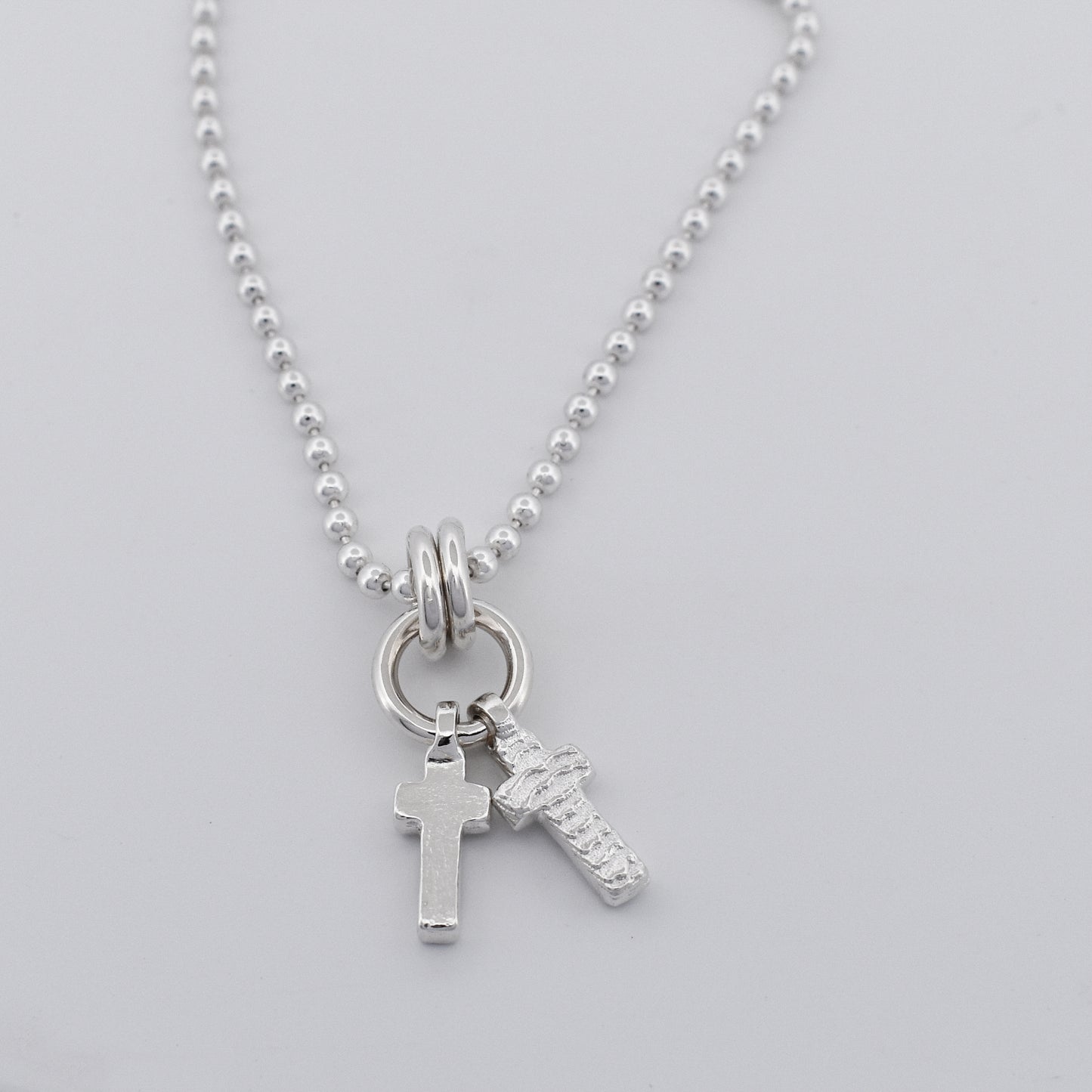 Sterling silver double cross necklace pendant hanging on a sterling silver ball chain