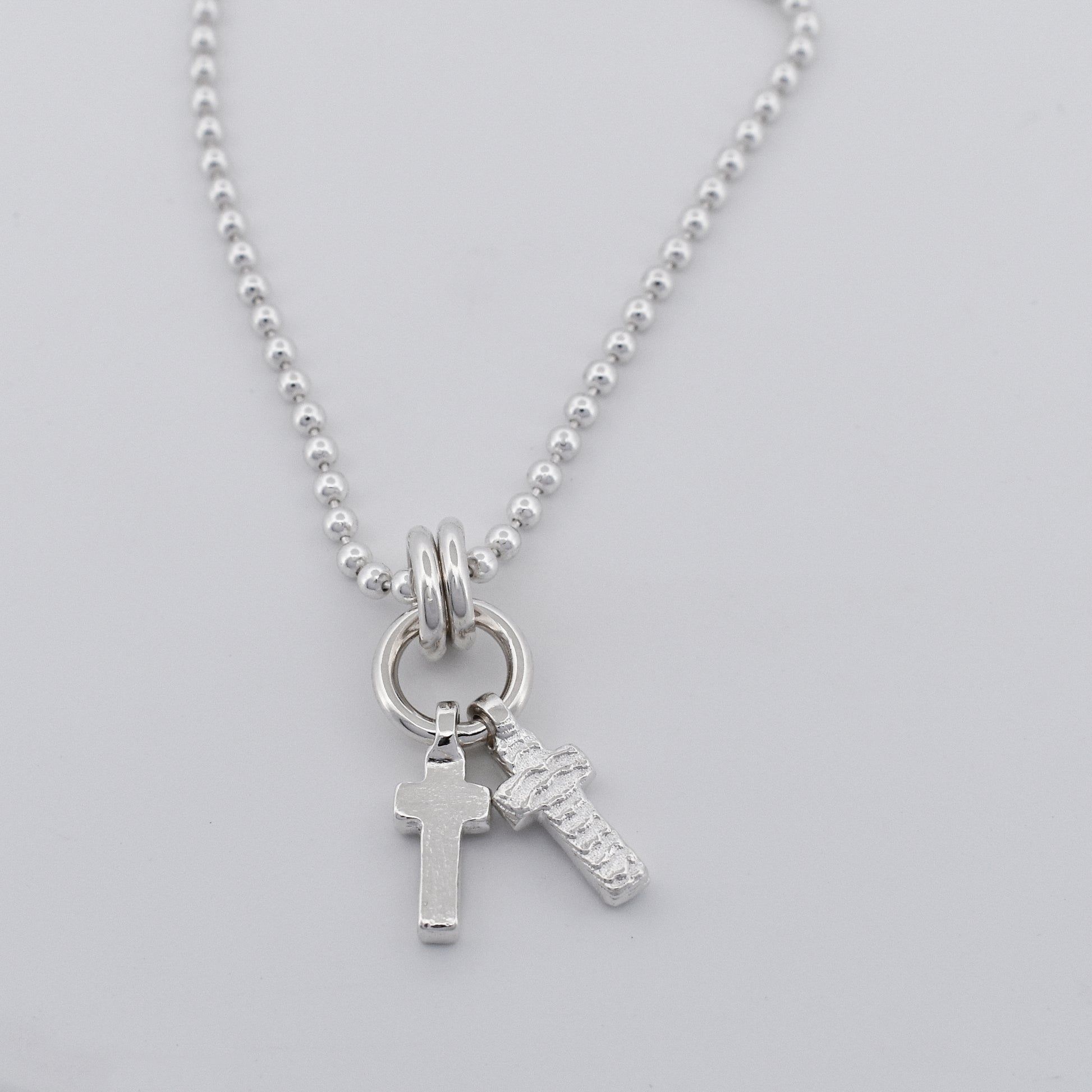 Sterling silver double cross necklace pendant hanging on a sterling silver ball chain