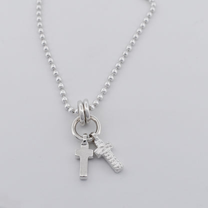 Sterling silver double cross necklace pendant hanging on a sterling silver ball chain