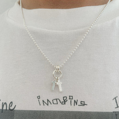 Sterling silver double cross necklace with one polished and one textured cross hanging on a ball chain, shot on model