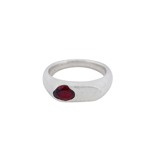 Product shot of an oval signet ring with a garnet gemstone set organically