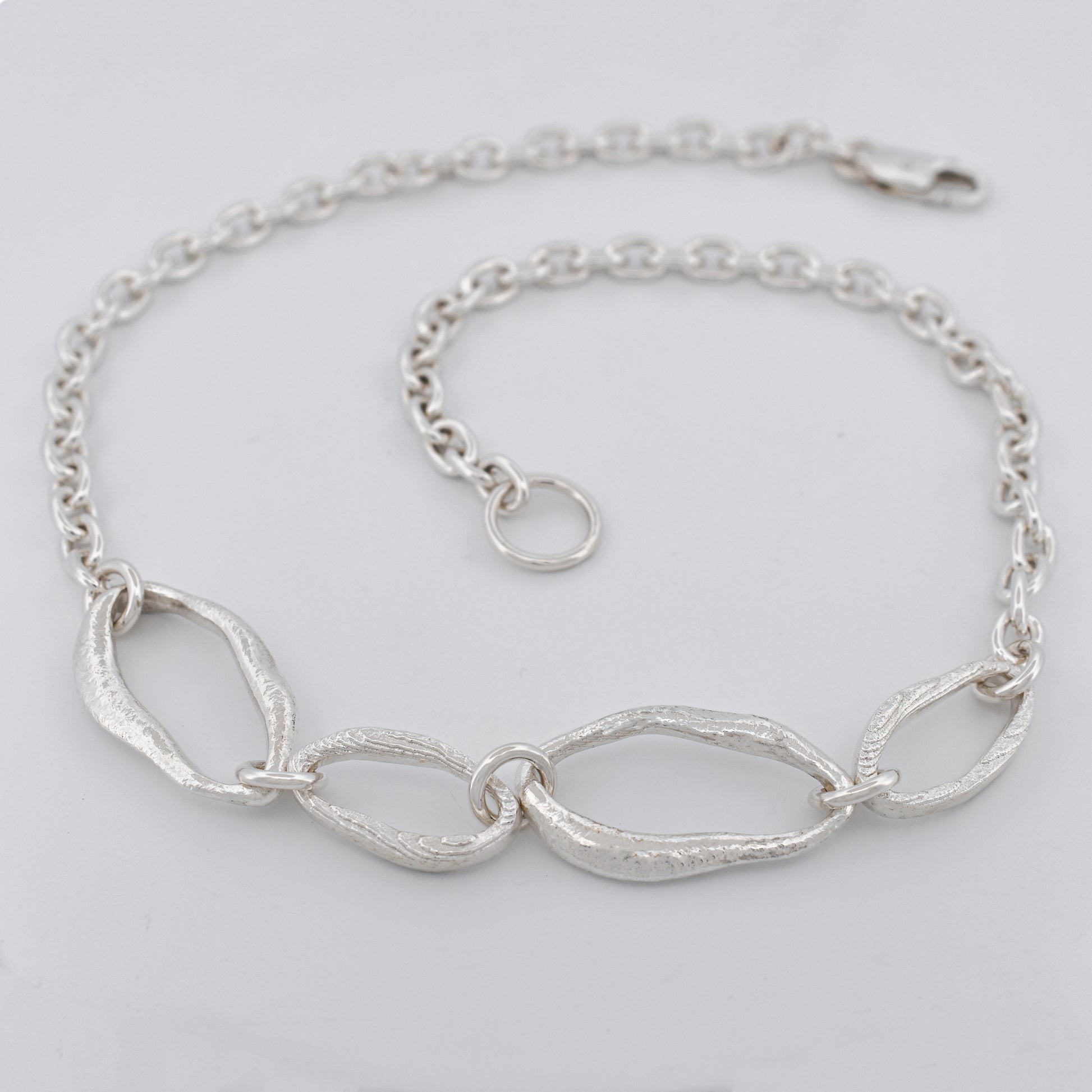 Sterling silver chain necklace featuring four sculptural links with raw textures